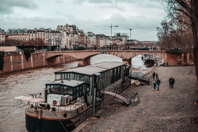 Péniche amarrée sur une rivière urbaine sous un pont en pierre