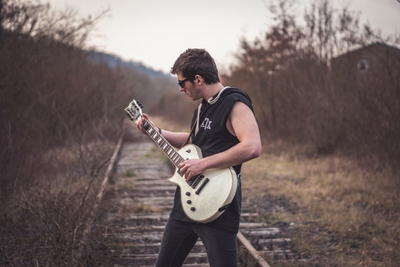 Homme avec guitare électrique sur une voie ferrée
